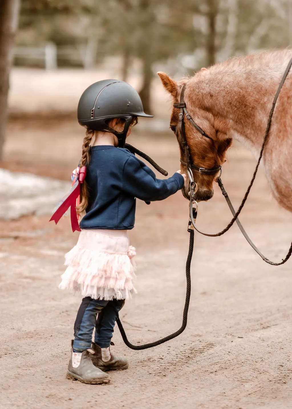 Child leading a pony with a ribbon braid