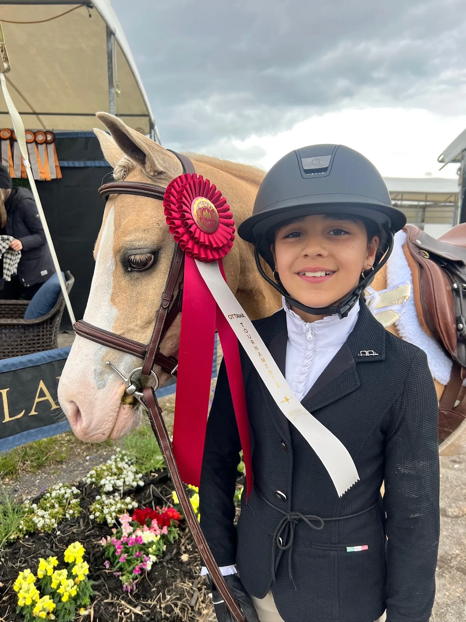 A young athlete with a palomino pony and a championship rosette at a show