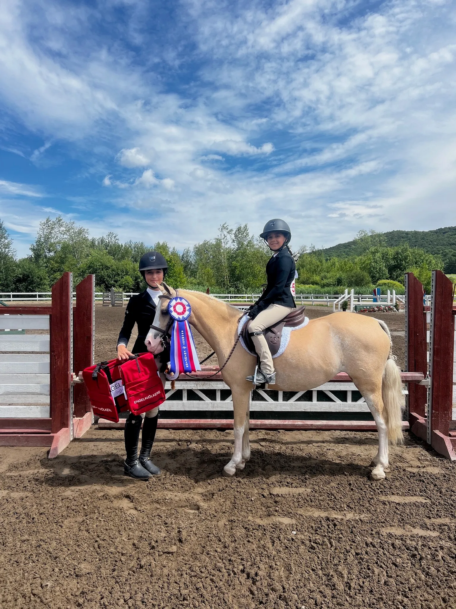 Two young athletes with their pony and a championship ribbon in the ring